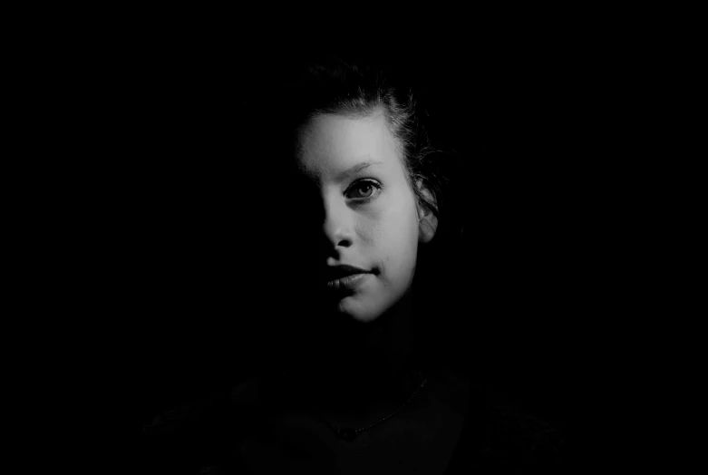 a young woman in a dark, dark room staring off into the distance