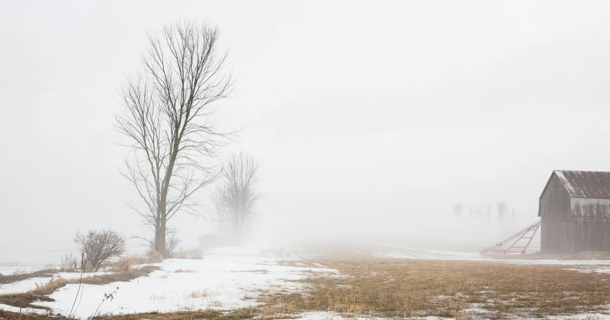 an old farm in the fog on a snowy day