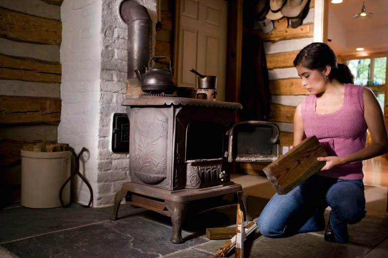 woman in pink shirt leaning over near wood stove