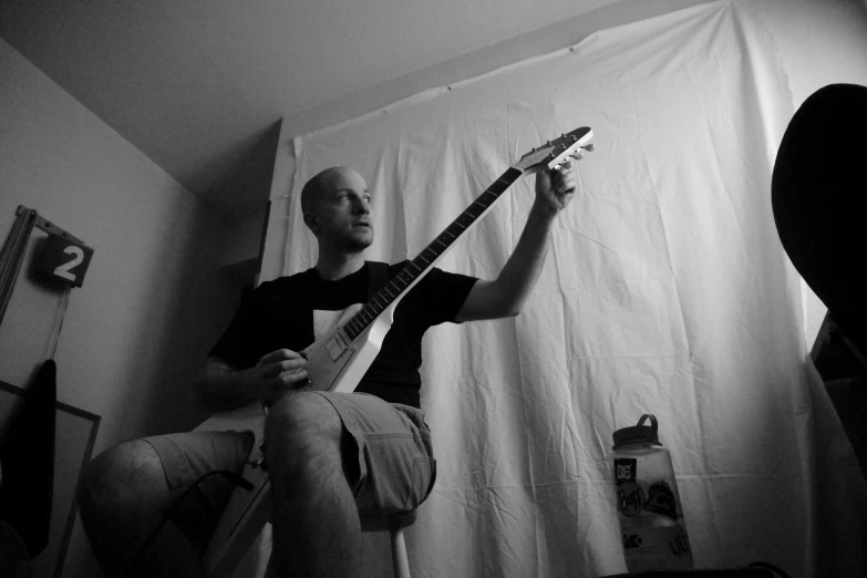 a man sitting on the floor while playing a guitar