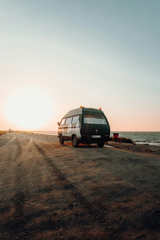 a small van sits on the shore near the ocean