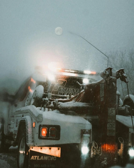 a tow truck driving down a road with snow on top