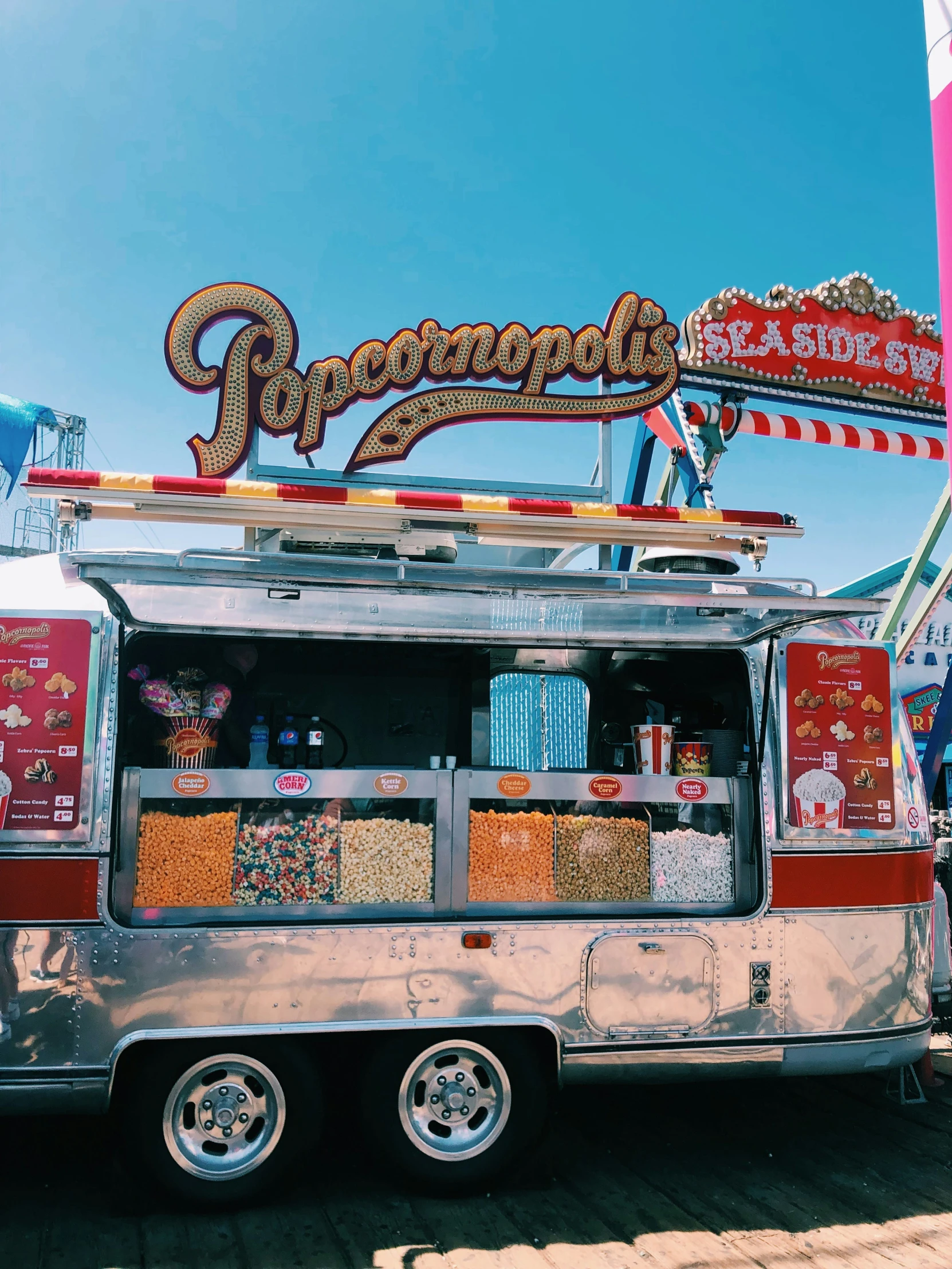 an old silver food truck with decorations and carnival signage