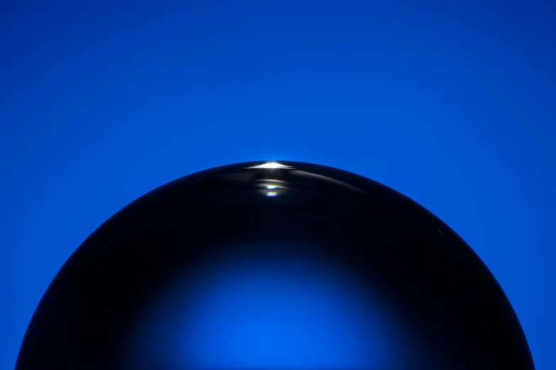 black sphere sitting on a table with a blue background