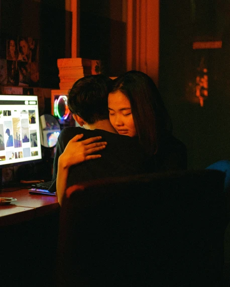 two people hugging each other in front of a computer