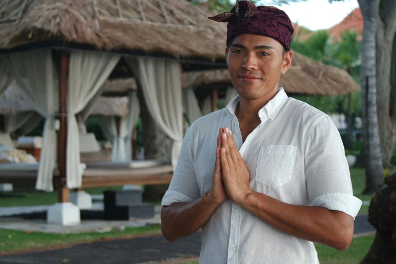 a man with a turban in his hands in front of an outside gazebo