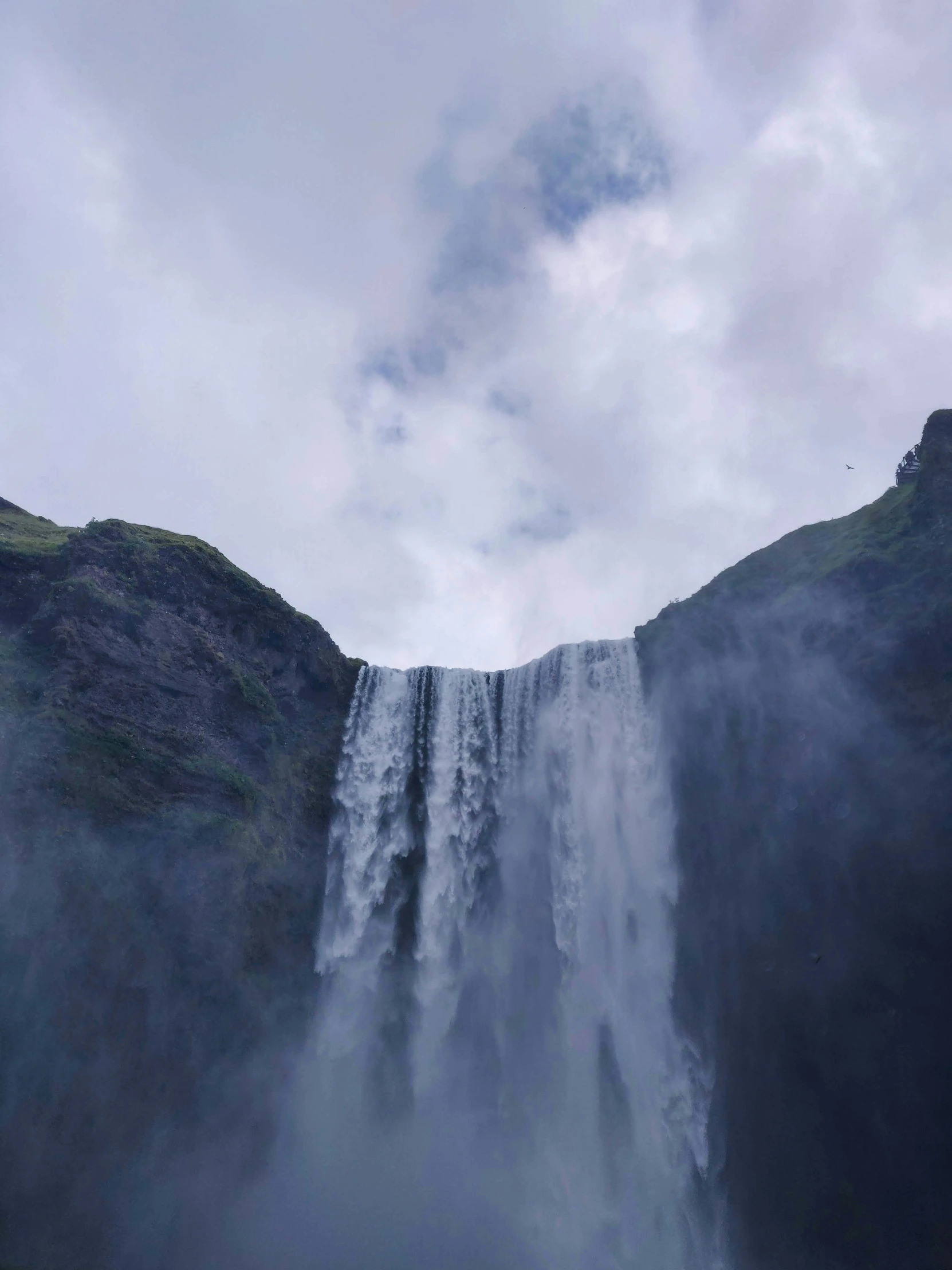 a waterfall seen from a distance and some birds flying by