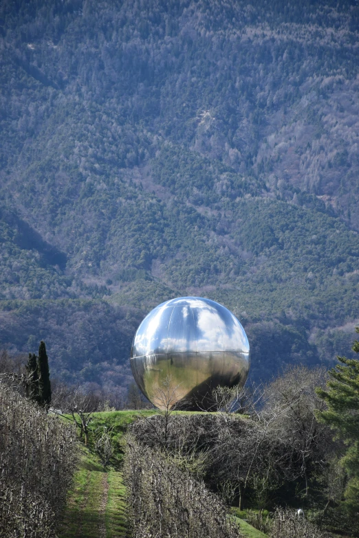 a metallic object is on a hill side near trees