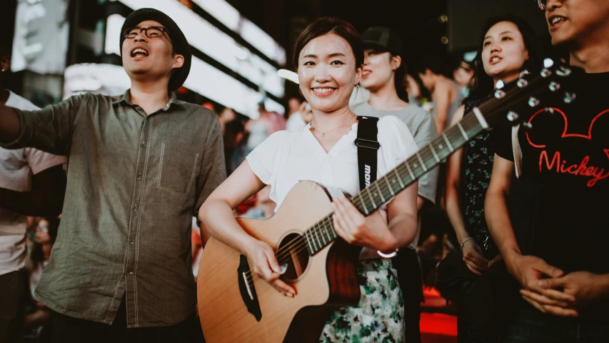 asian couple singing with acoustic guitar and girl smiling