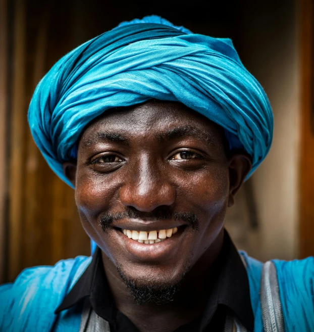 a man with a bright blue turban smiling for the camera