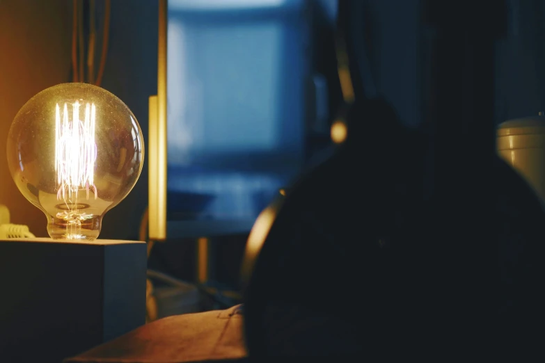 an old fashioned lamp lit next to a bookshelf