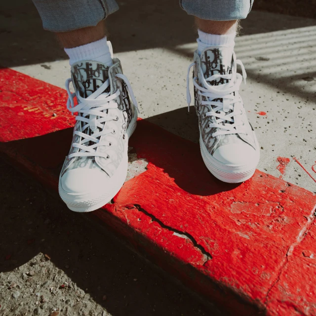 person's feet with tennis shoes standing on top of red painted step