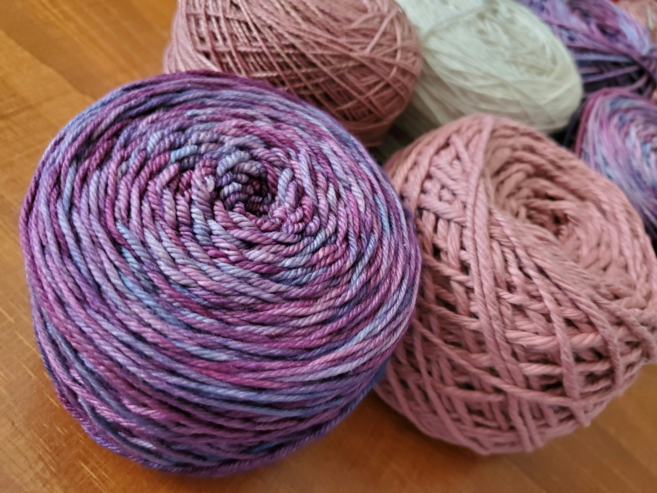 a couple of balls of yarn sitting on top of a wood floor