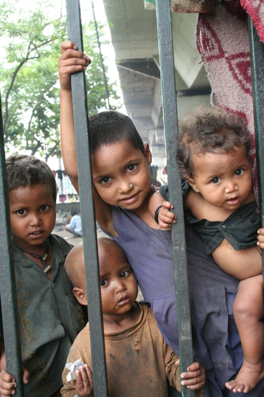 a group of children standing behind a metal fence