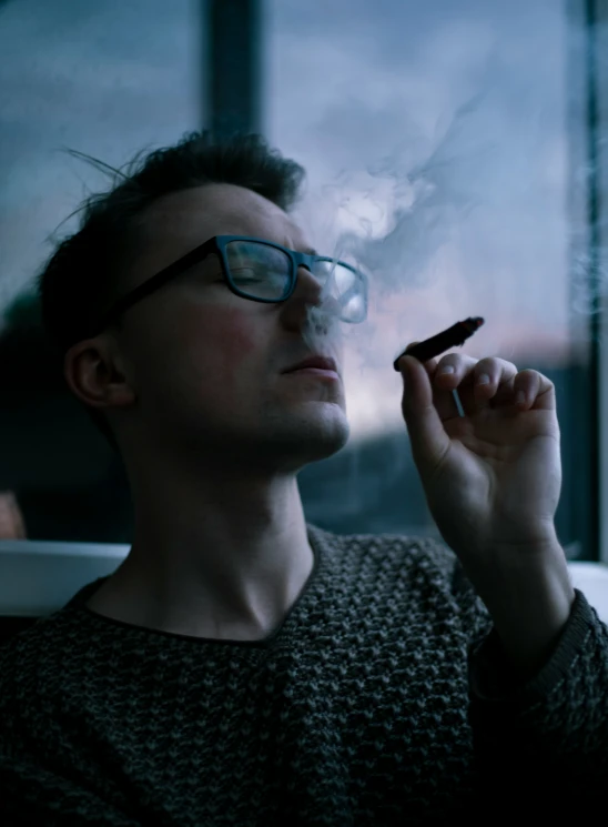 a man smoking a cigarette while looking out the window