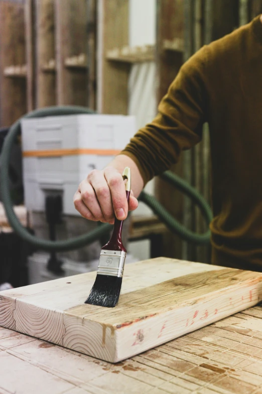 a person paints a block of wood with a brush