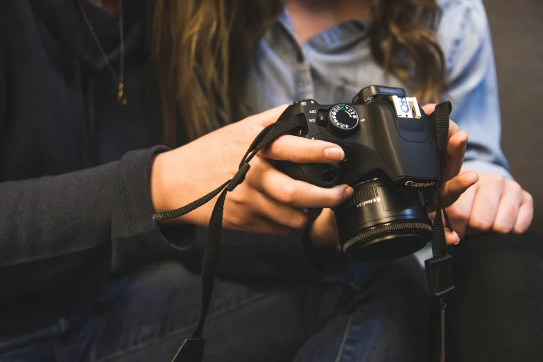 two people sitting next to each other with camera and lenses