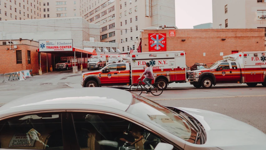 ambulances, cars and a person on a bicycle on a street