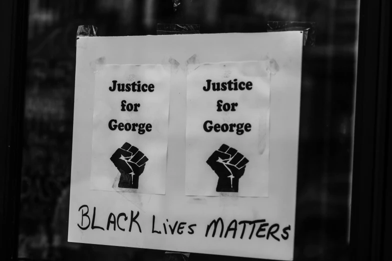 two signs posted to a window reading justice for george and black lives matter