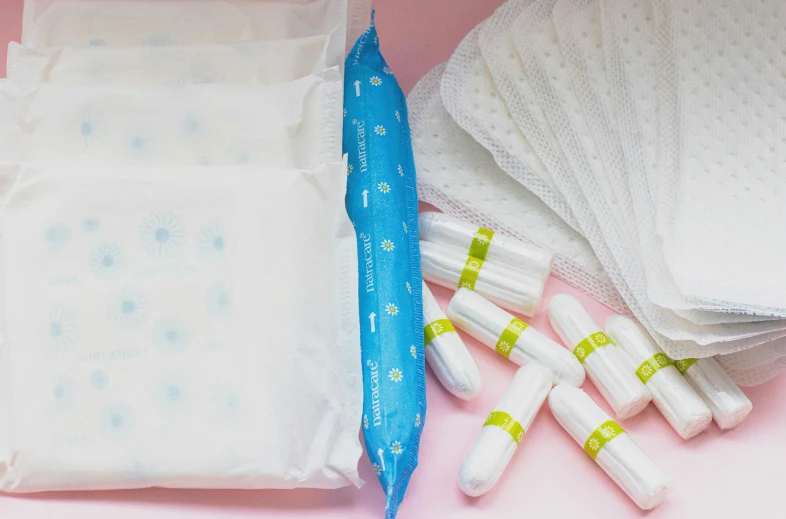 four sanitary pads and six medical pills sit atop the white cloth