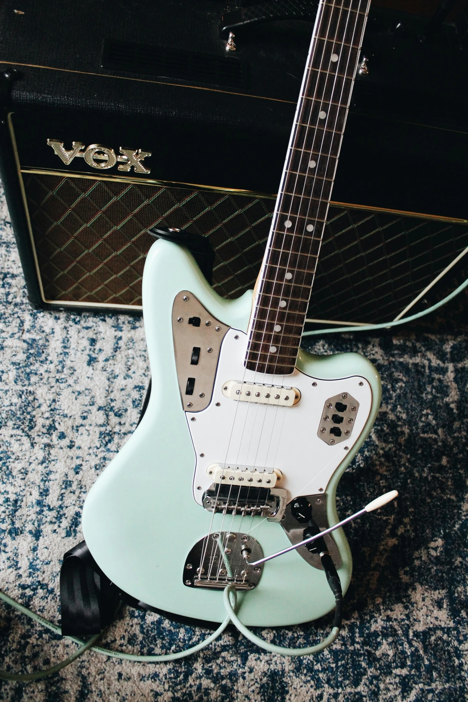 a guitar sitting on top of a blue carpet next to an amp