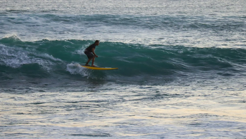 a man in a wet suit is surfing on a yellow surfboard