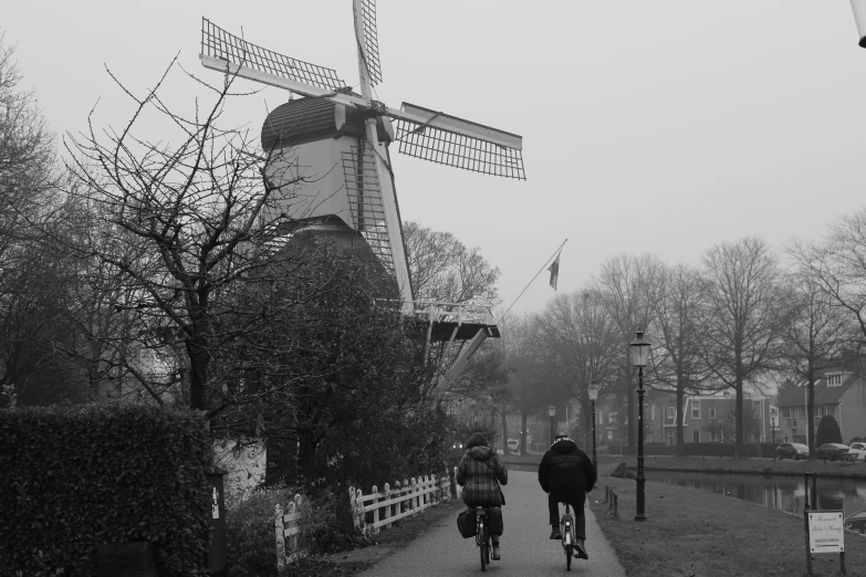 a person on a bike is passing near a windmill