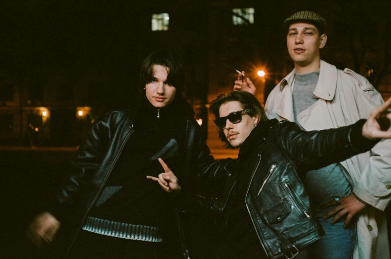 three young men, one smoking and one holding up their cigarette