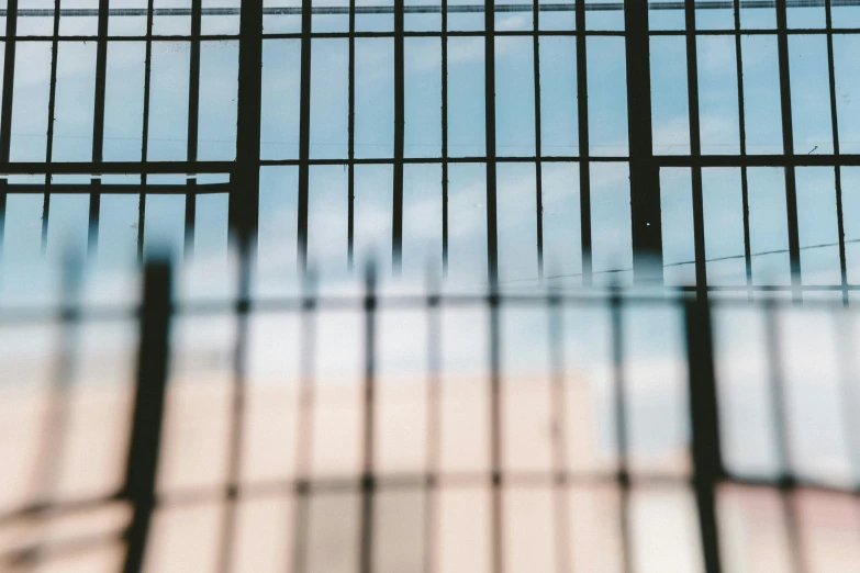 the top part of an iron fence with a blue sky in the background