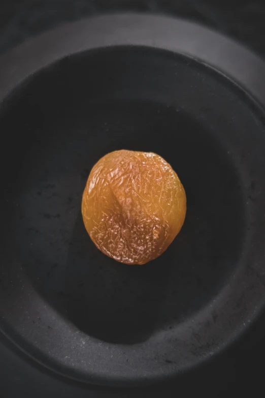 an orange on a plate sitting inside of a black bowl