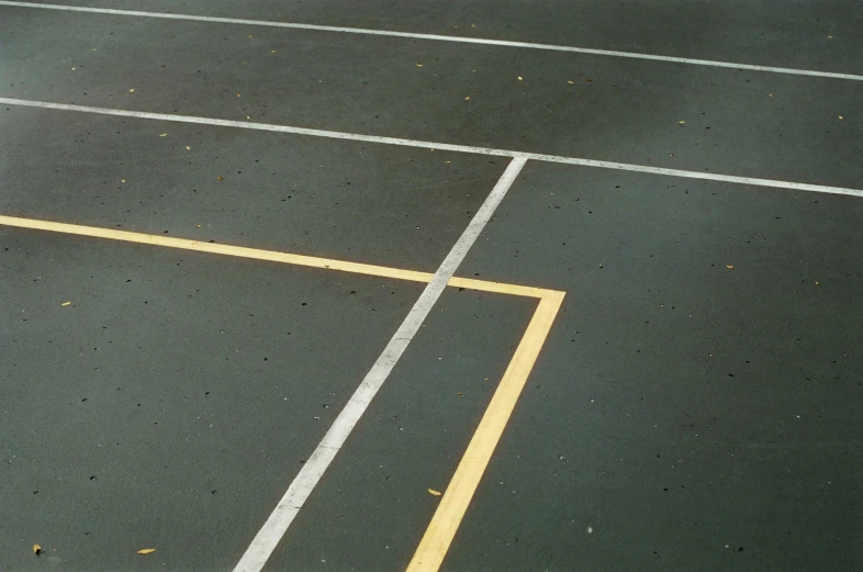 a yellow fire hydrant with a black top in the middle of an empty parking lot