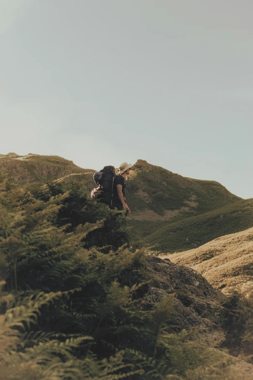 a person hiking up the side of a green mountain