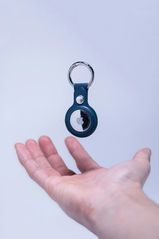 hand holding a small key ring in front of a white wall