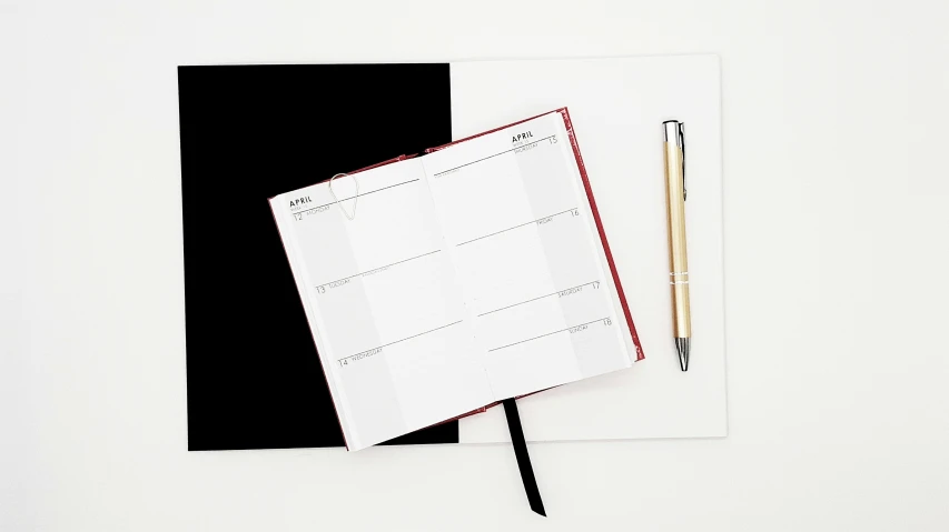 an open notebook with paper, pencil and black ink