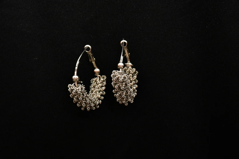 a pair of earrings sitting on top of a black surface