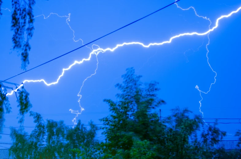 lightning streaks over a forest at night time