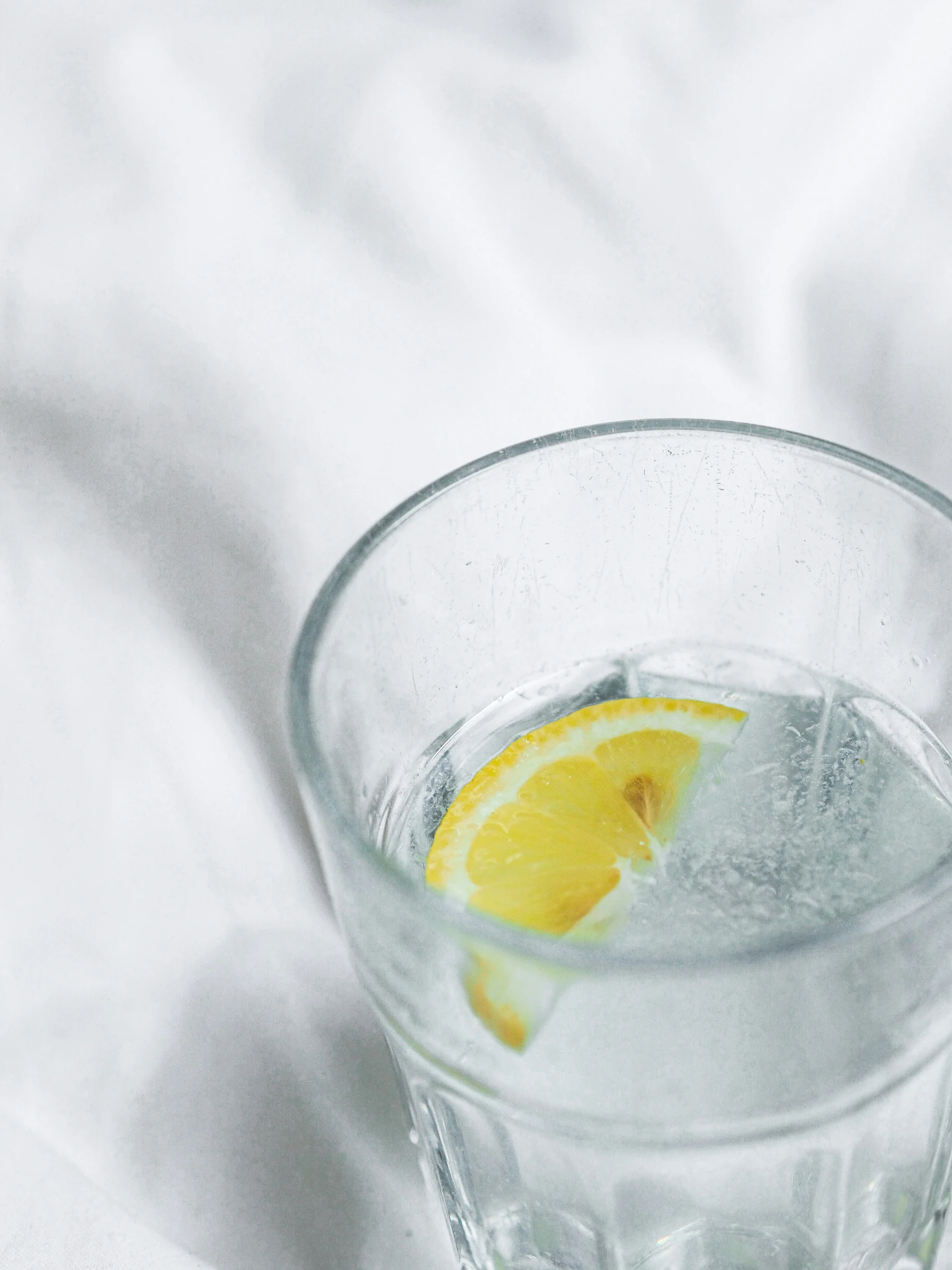 a glass cup with ice and a half lemon