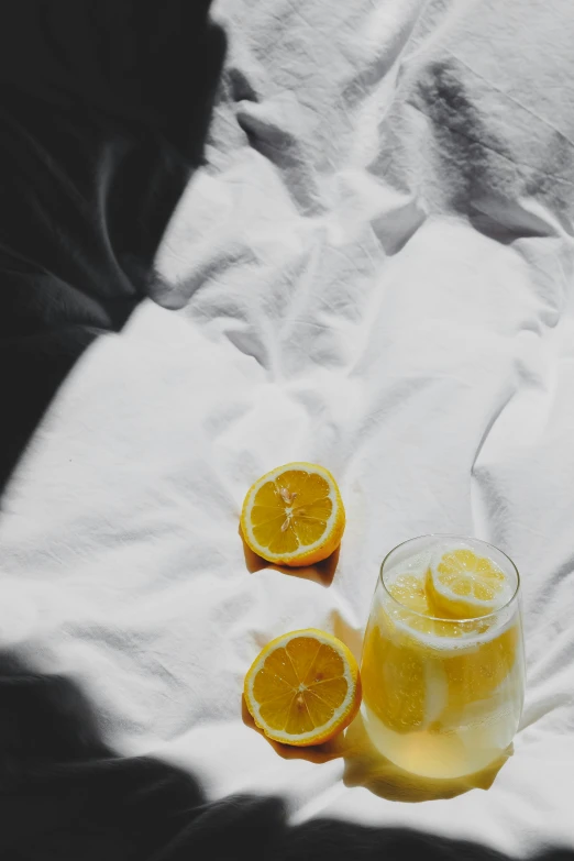 three oranges and one beverage sitting on a white blanket