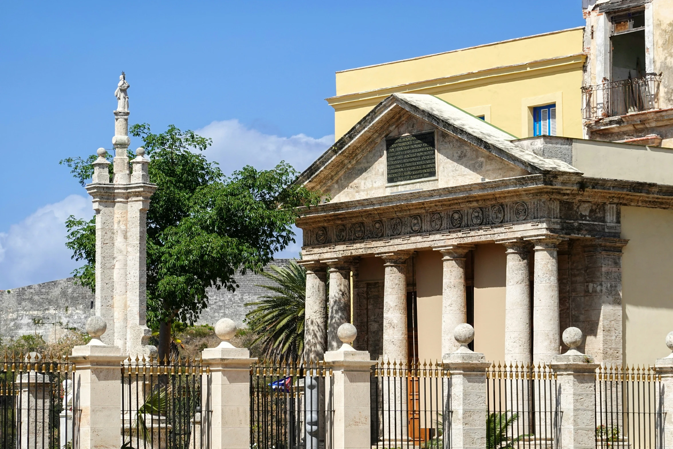 there is a building on a corner with two pillars and a clock tower behind it