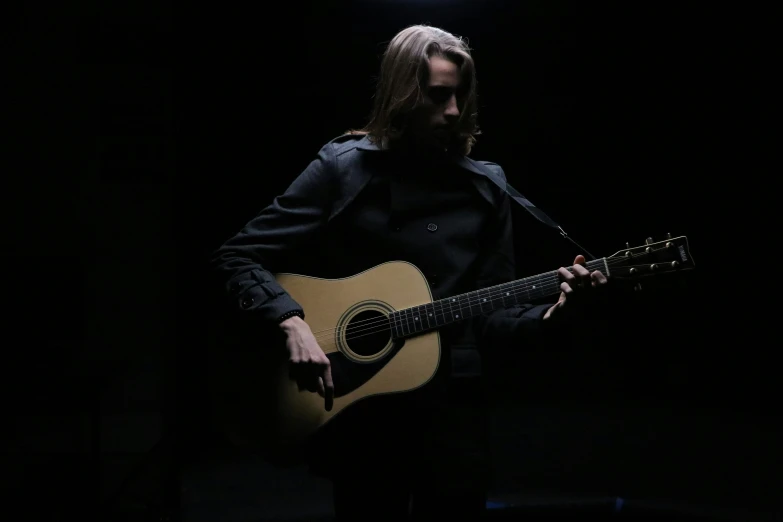 the man is playing his guitar in the dark