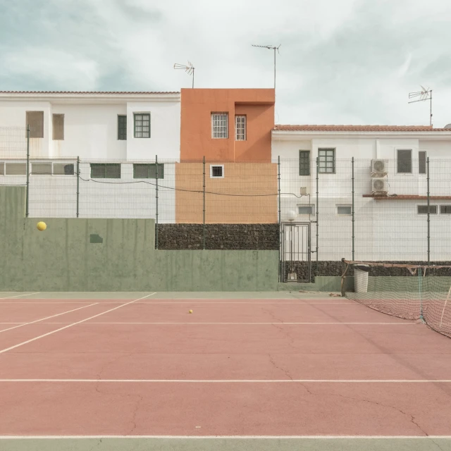 a tennis court that is fenced in with a tennis ball
