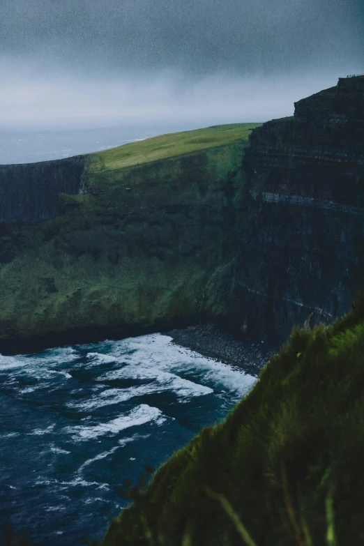 an ocean view with a grassy cliff behind it