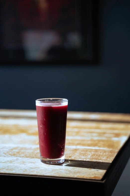 a glass filled with red liquid sitting on a table