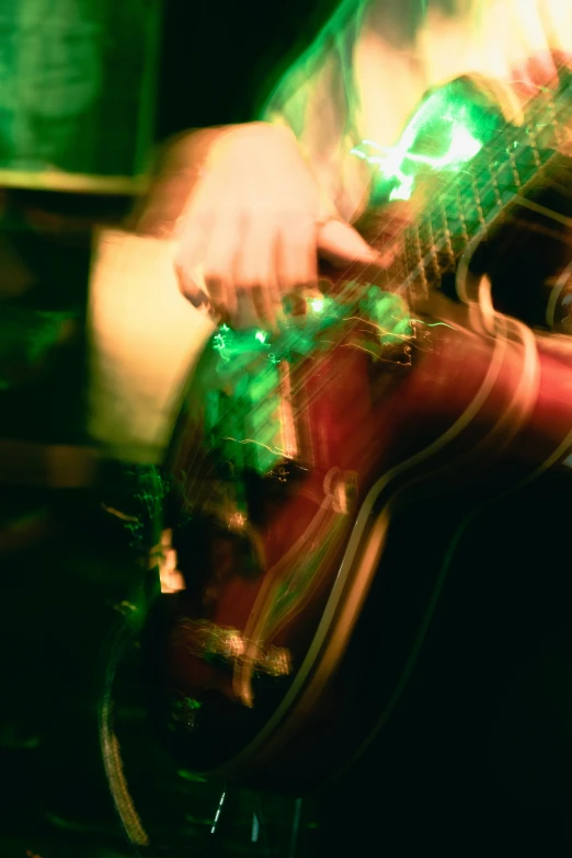 a person that is playing the guitar and has a dark background