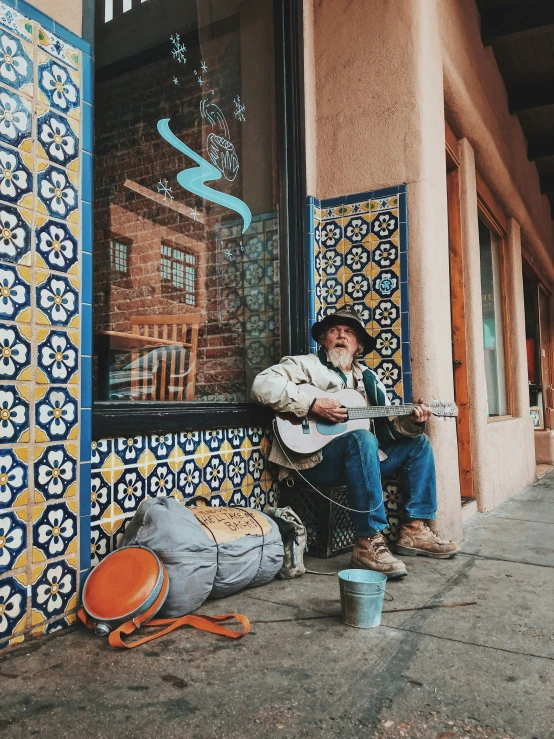 a man sitting on the side of the street playing guitar