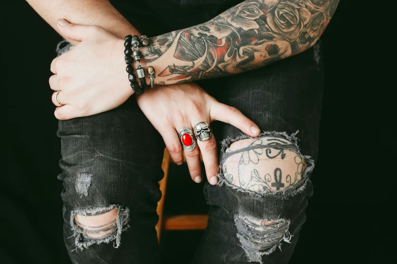 two men with tattoos and red ring holding hands