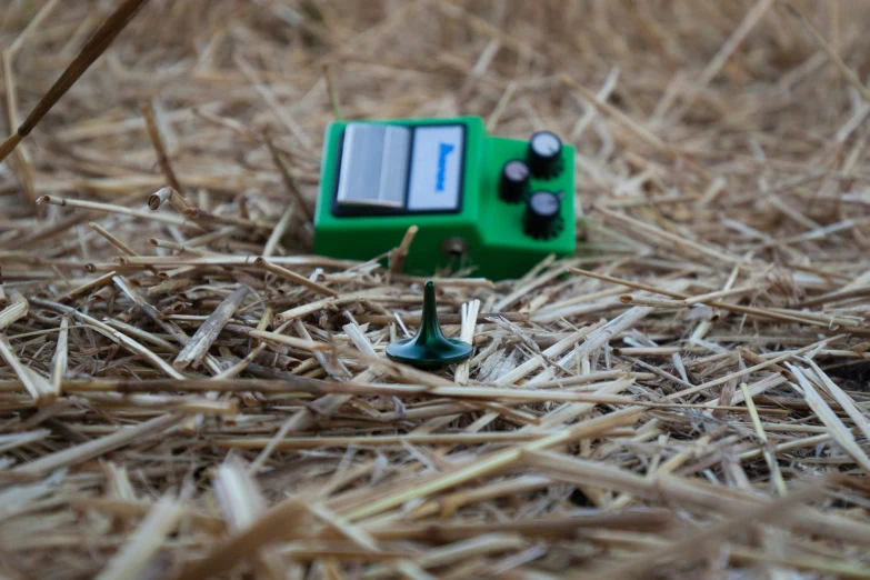 a green device is sitting on straw in the woods