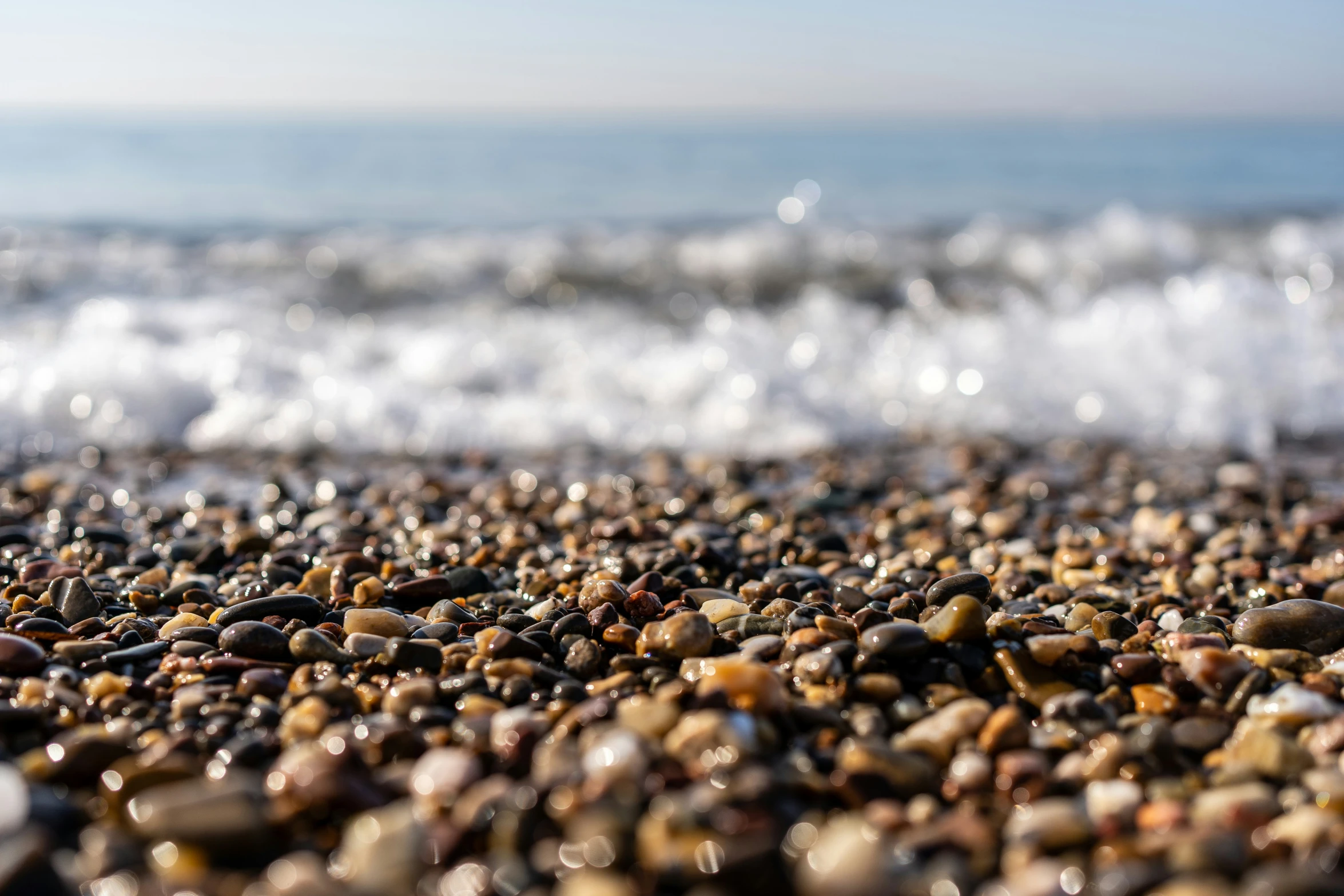 many different rocks on the beach near water