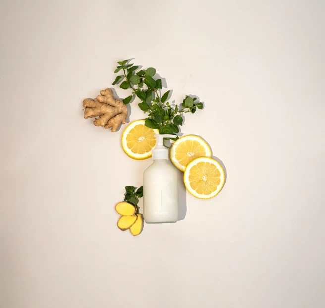 a white vase with lemons, and ginger next to an arrangement of gin