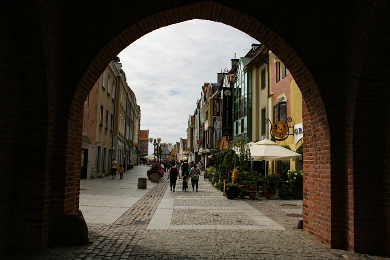 a few people walk underneath a large brick arch